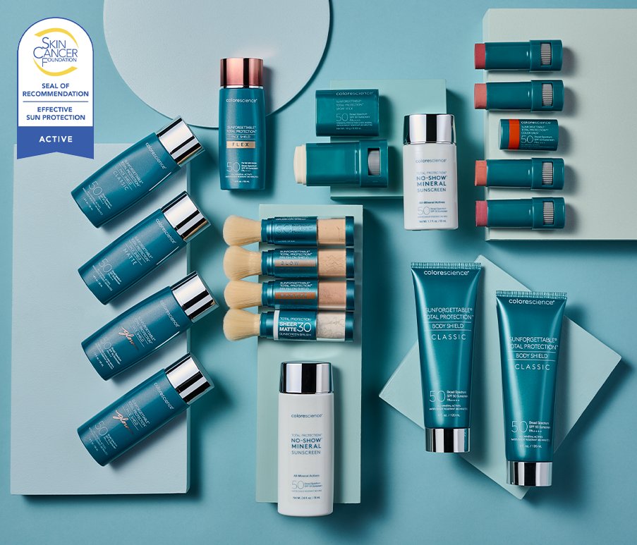 Colorescience products displayed on a wooden table outdoors in the Spring with lush green foliage with white flowers in the background.