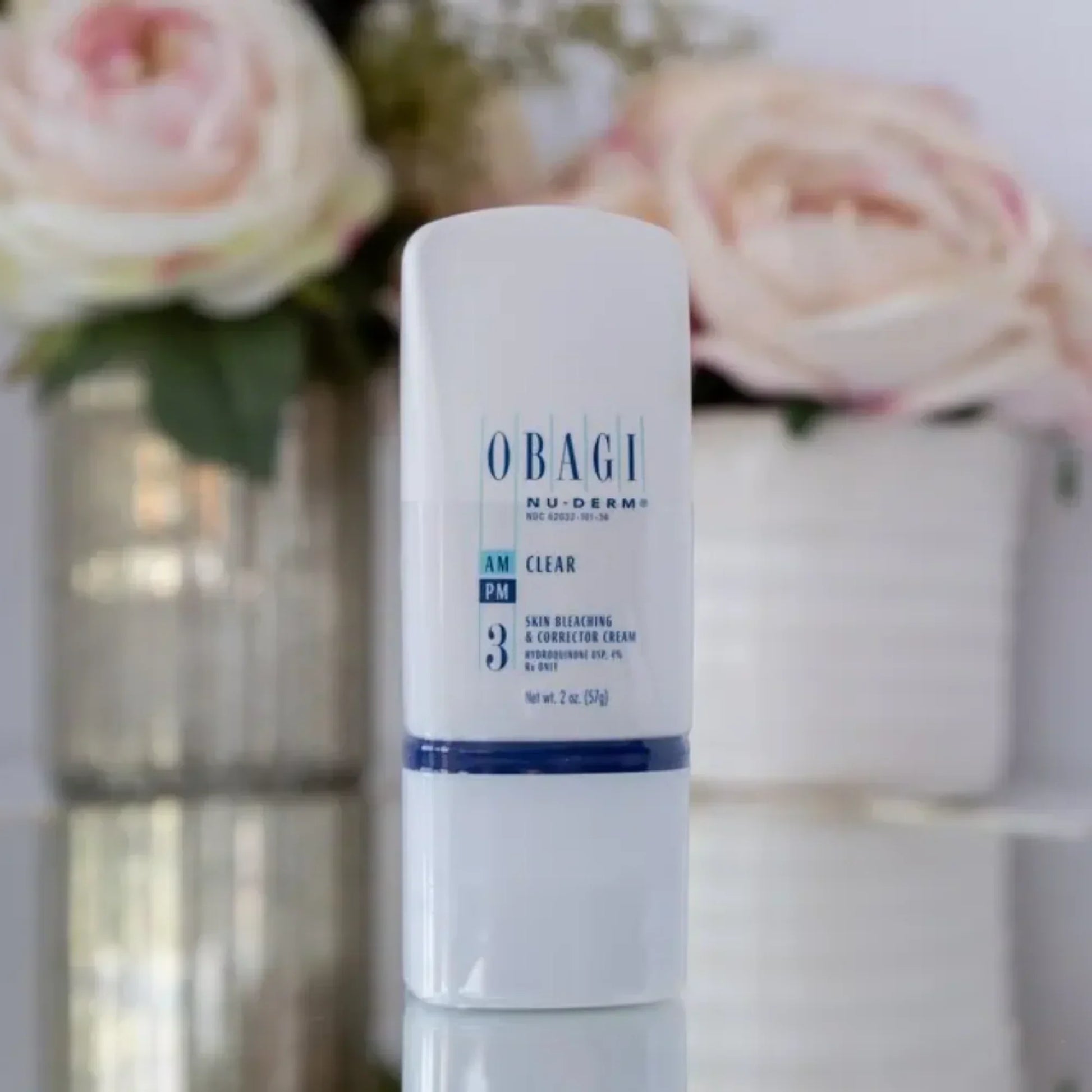 Obagi Nu-Derm Clear skincare cream bottle on counter with flowers in background