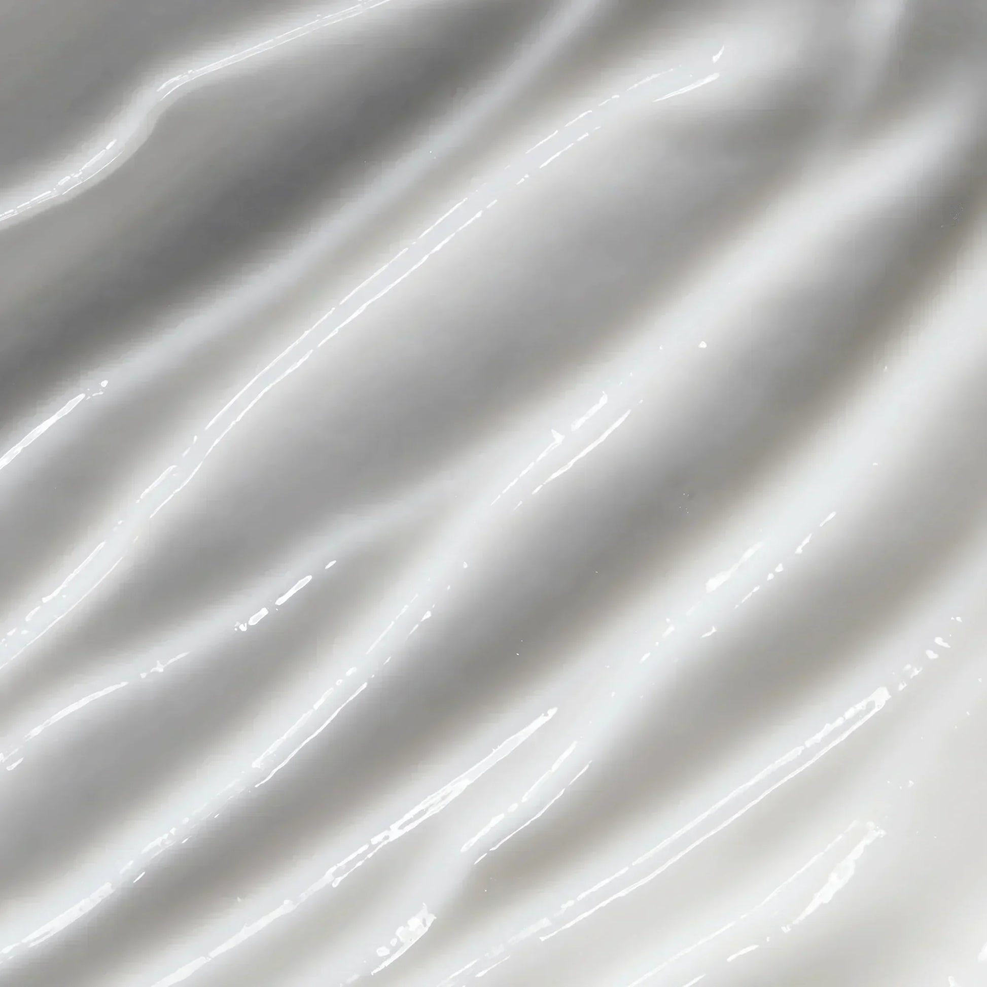 Close-up of creamy skincare lotion texture with glossy, smooth white swirls