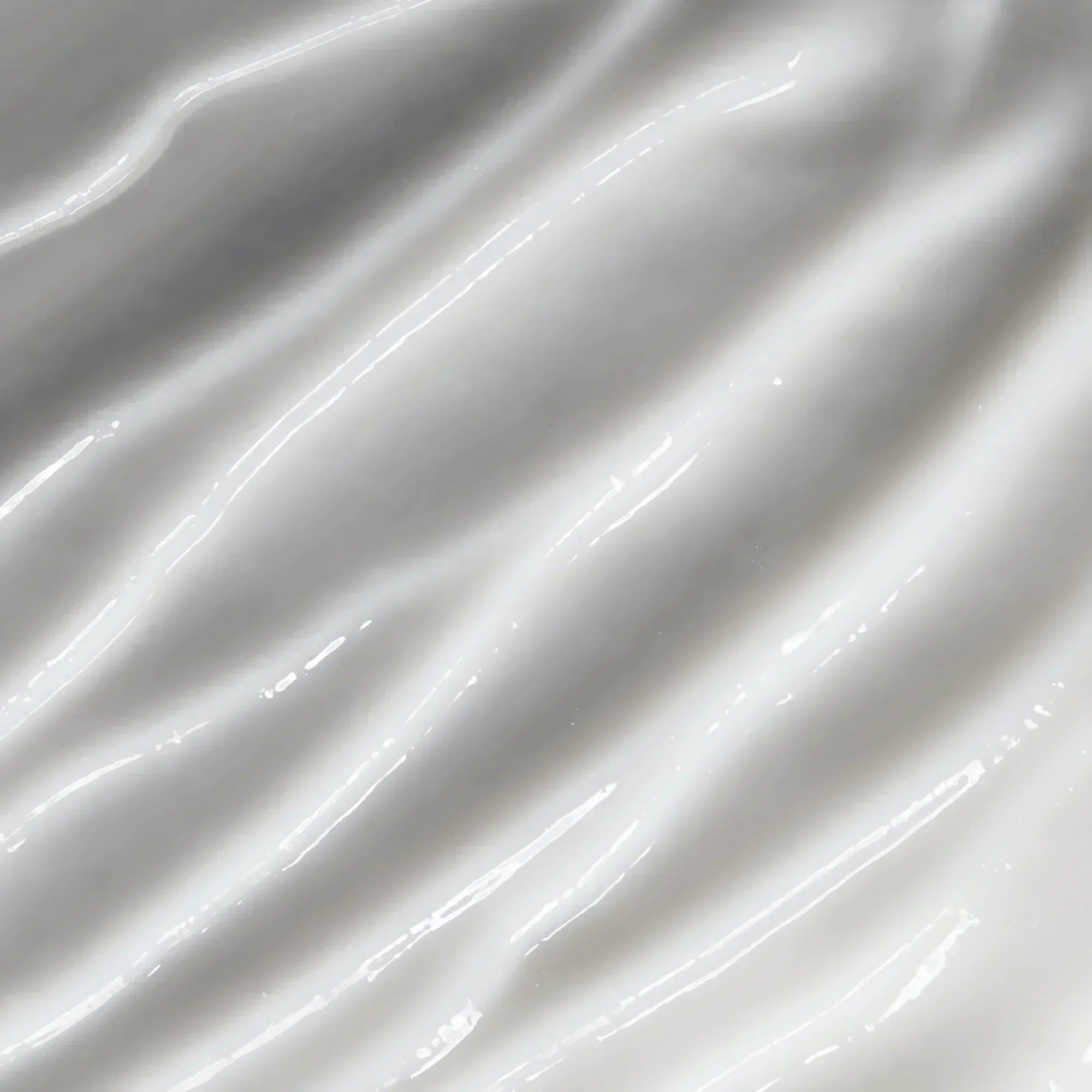 Close-up of creamy skincare lotion texture with glossy, smooth white swirls