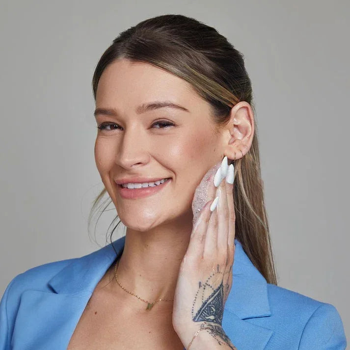 Smiling woman cleansing face with foaming exfoliating wash, promoting skincare routine
