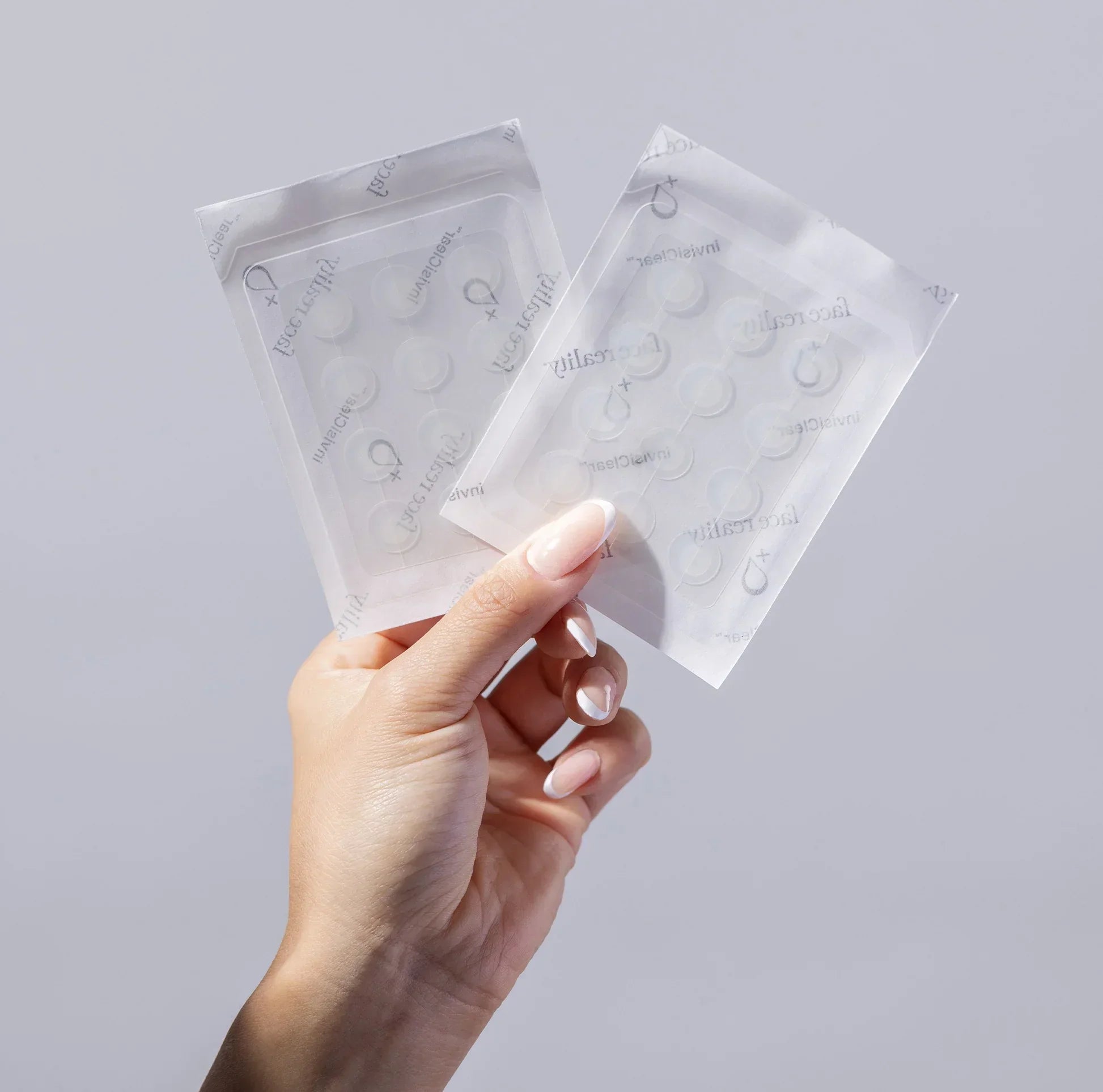 Hand holding two packs of clear acne patches for blemish treatment