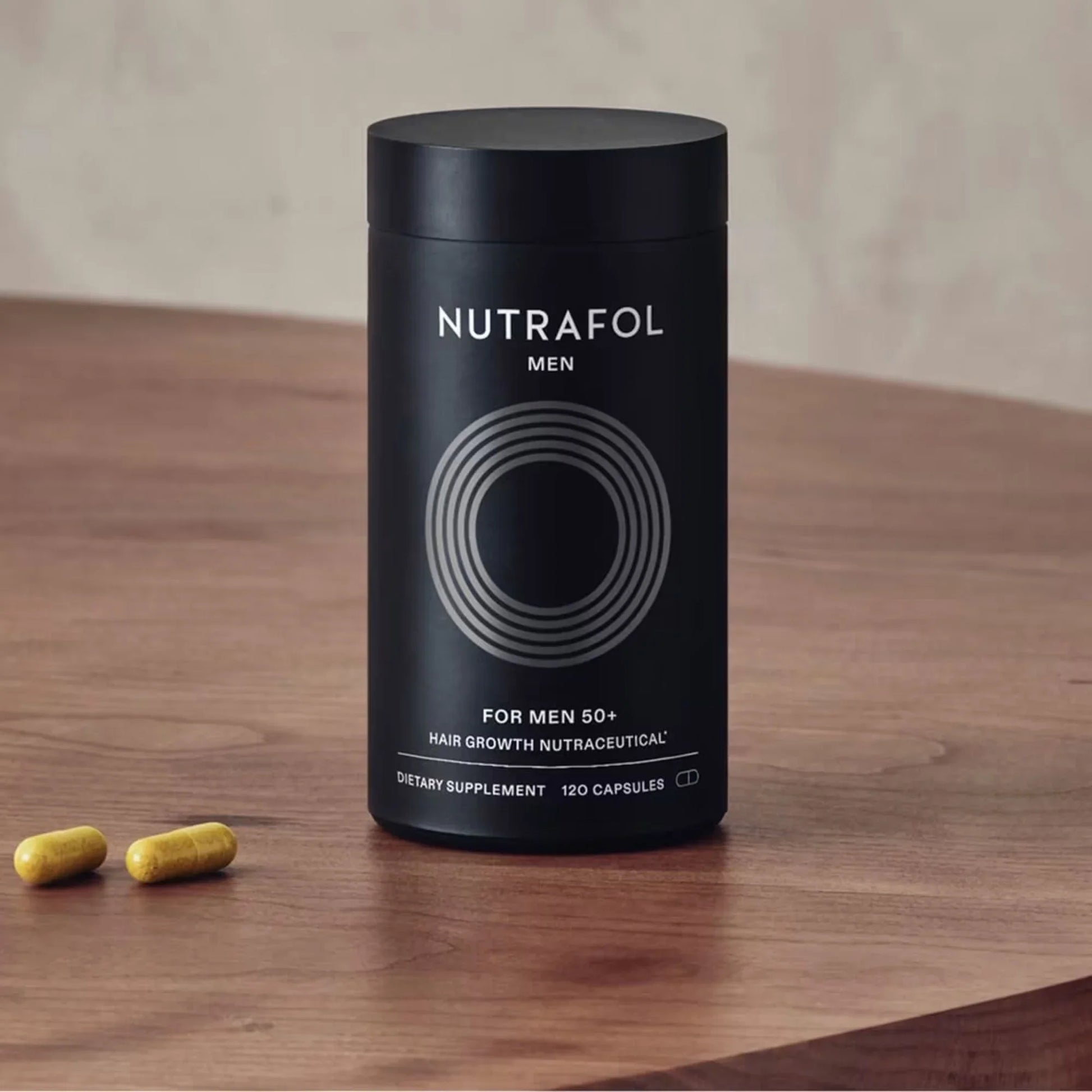 Nutrafol Men 50+ hair growth supplement bottle with capsules on wooden table