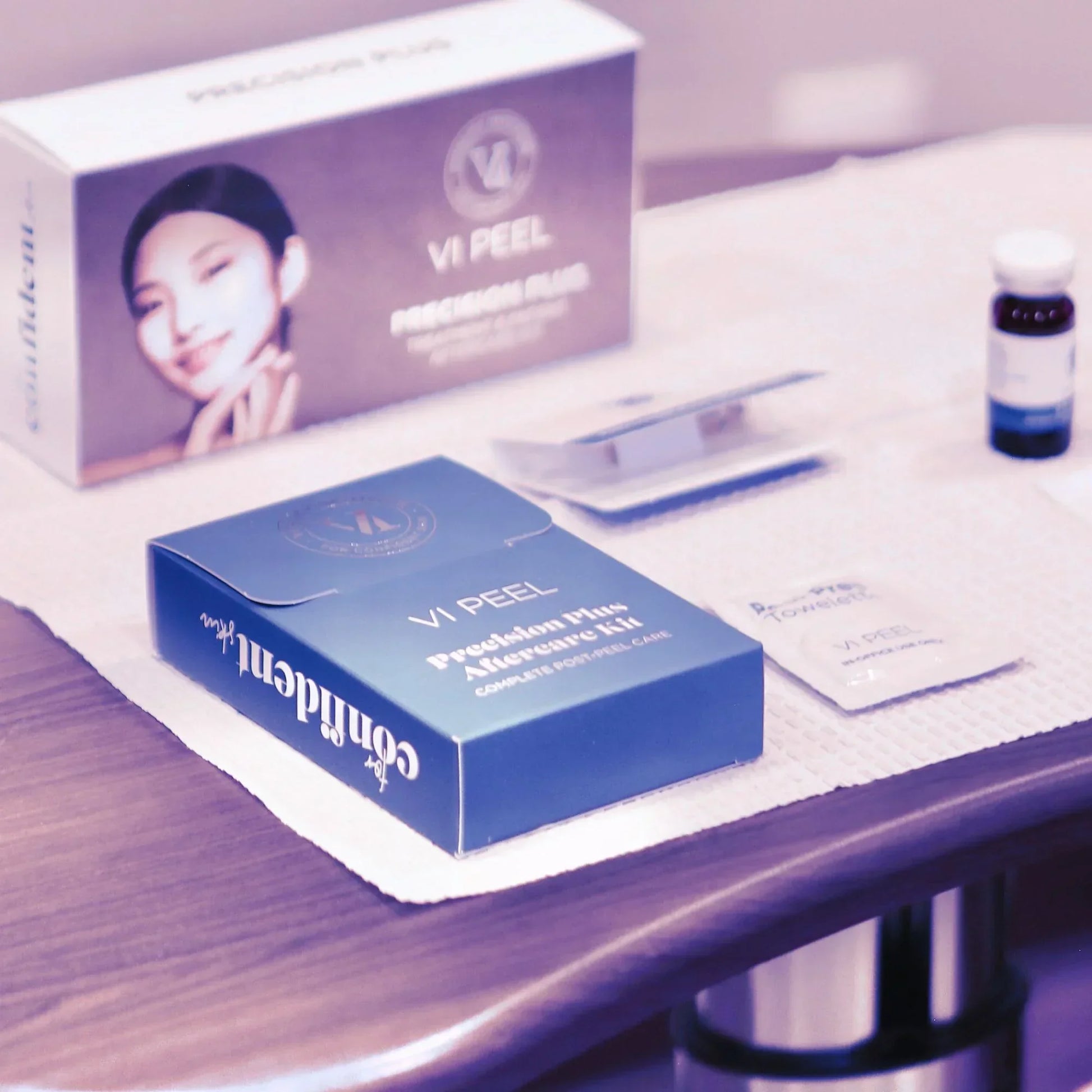 VI Peel Precision Plus skincare kit box, serum vial, and treatment packets on treatment table