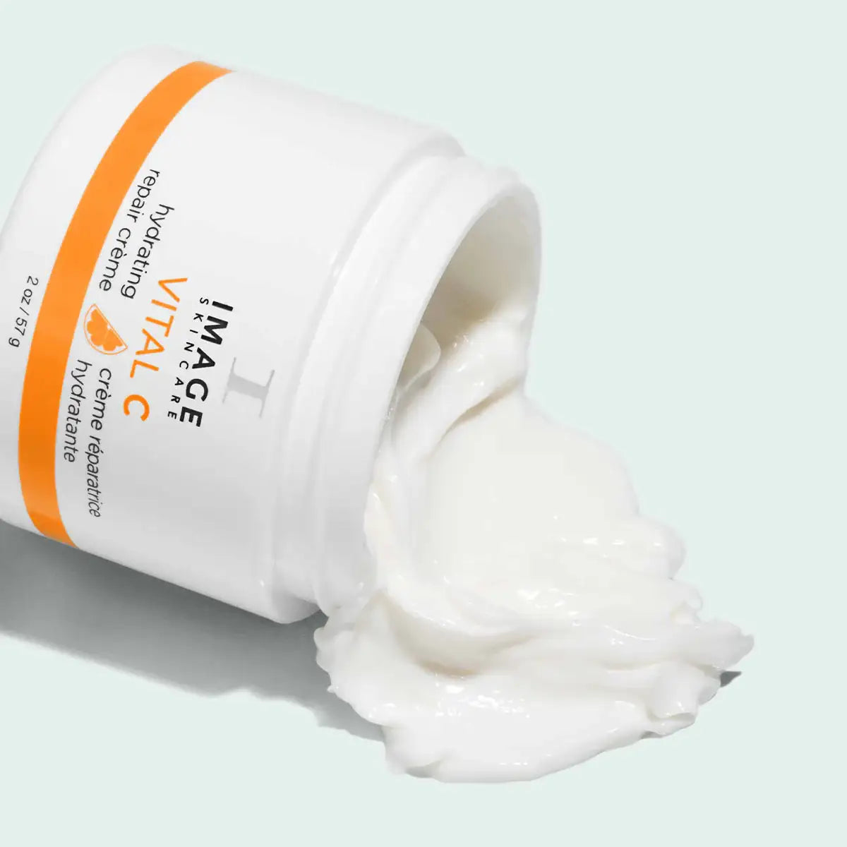 Open jar of hydrating repair crème with creamy texture spilling out, skincare product